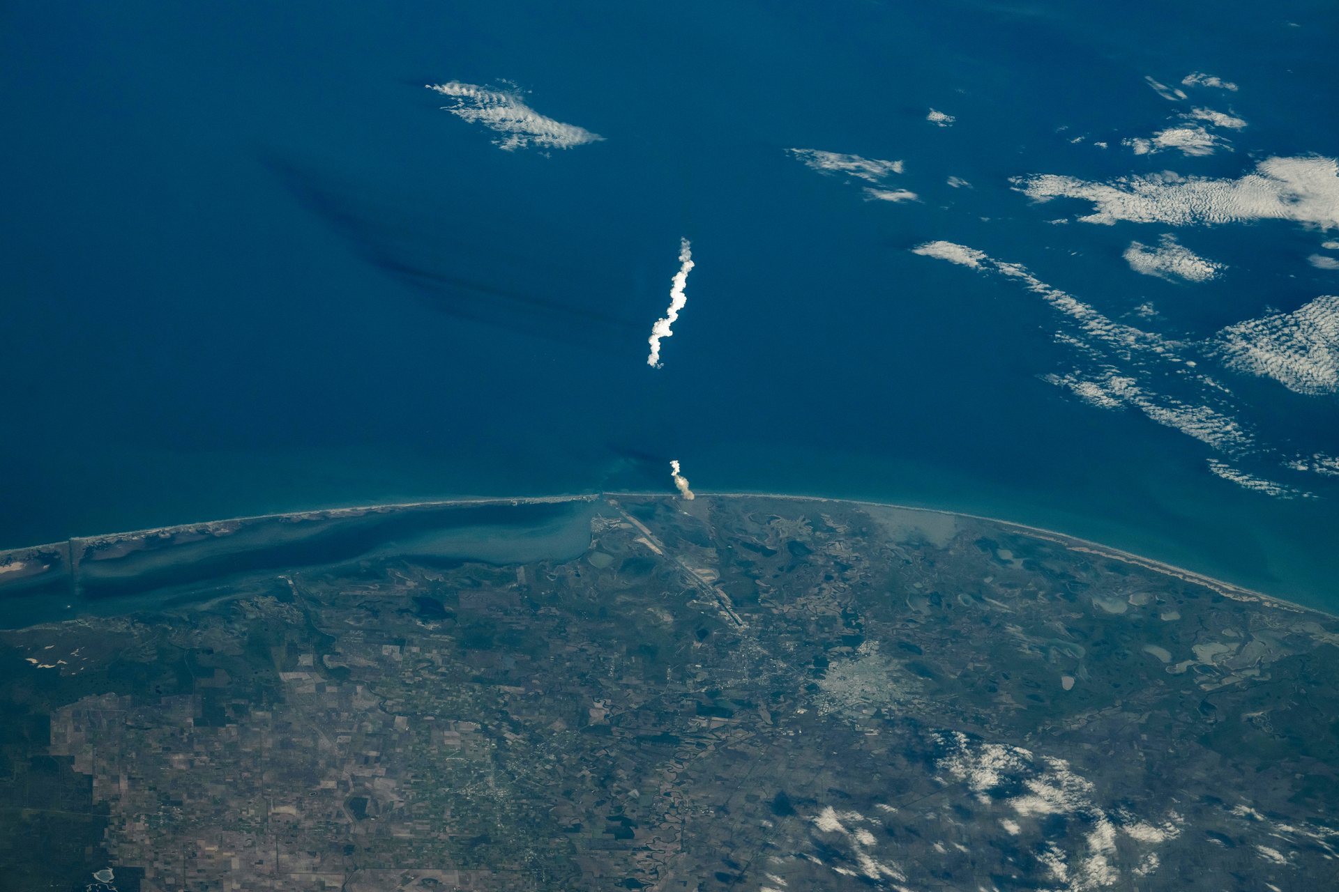 The exhaust plume of a SpaceX Starship rising over the Gulf coast from Starbase, Texas, photographed by an astronaut aboard the International Space Station on November 19, 2024, during Starship's sixth flight test. NASA photograph.
