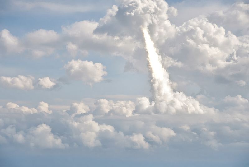 Illustration: a rocket's plume climbing through clouds. Not a photo of this launch.